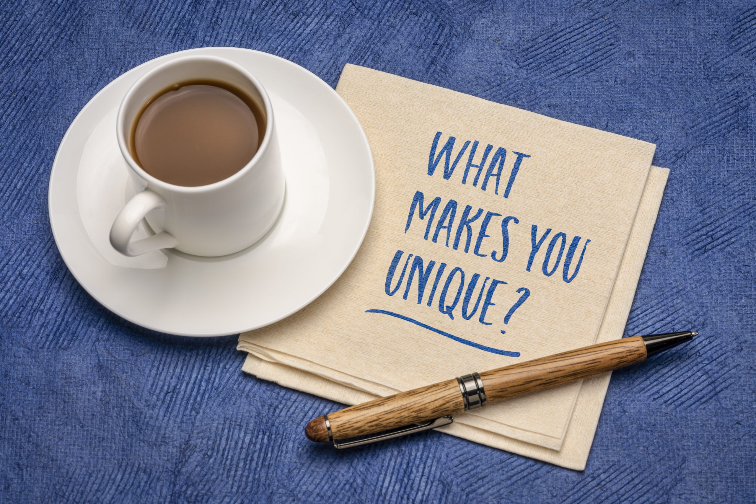 napkin with the words what makes you unique written on it next to a cup of coffee