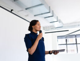 mixed race businesswoman wearing smart clothes, standing in an empty modern meeting room, training herself before the conference
