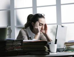 stressed woman at work with piles of folders around her